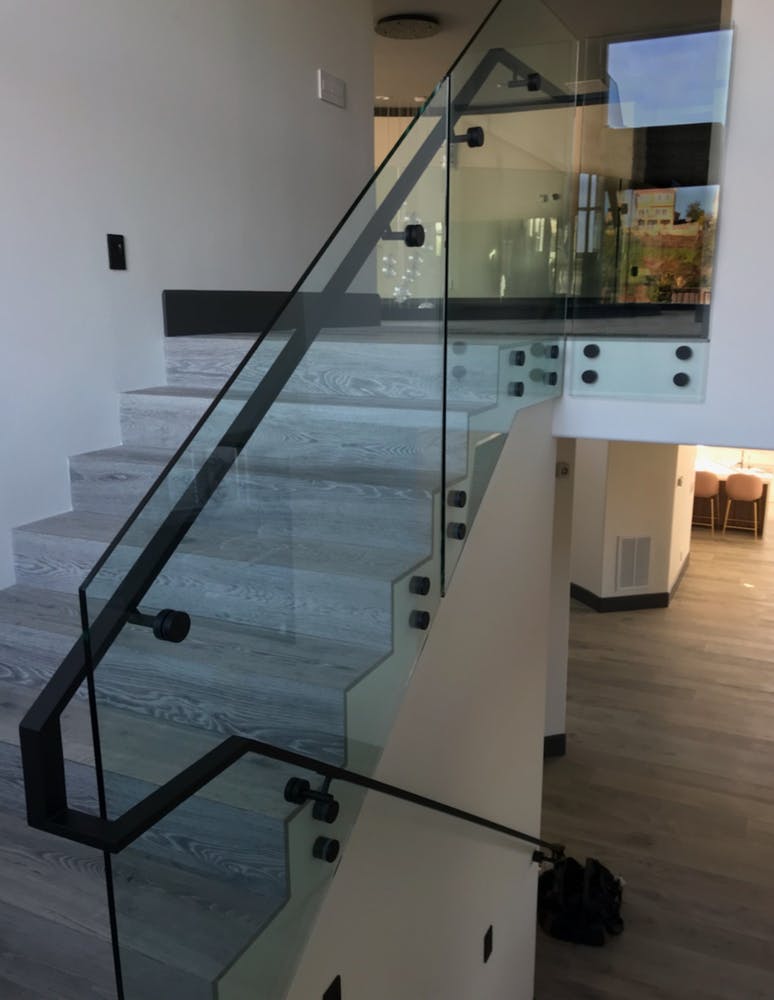 Glass staircase with black steel railing surface mount stand-offs