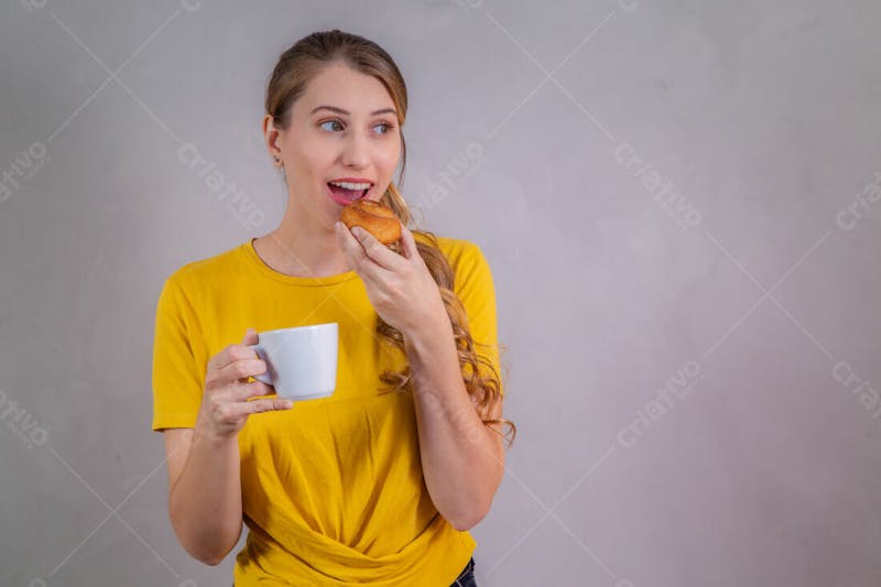 Jovem bonita loira comendo donuts chocolate tomando café camiseta amarela 1