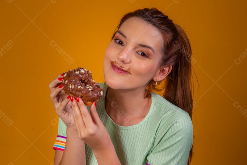 Jovem bonita comendo donuts chocolate camiseta verda 1