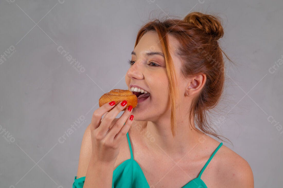 Mulher comendo doce sorrindo fundo cinza