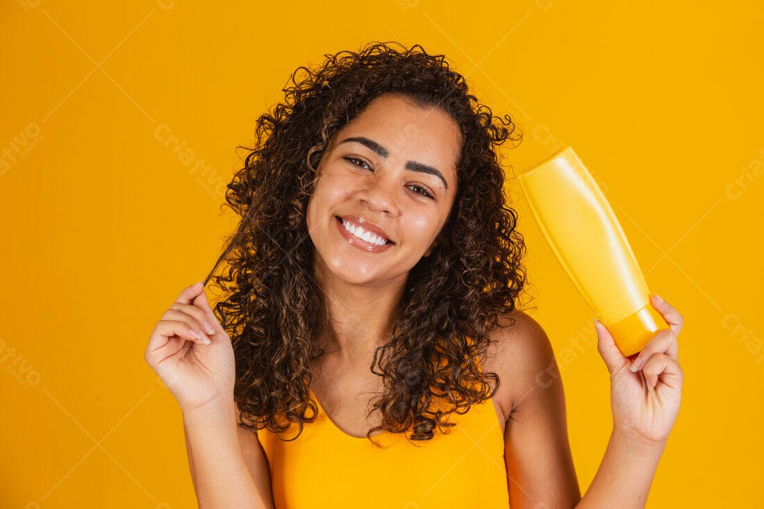 Mulher feliz com cabelo cacheado segurando shampoo amarelo