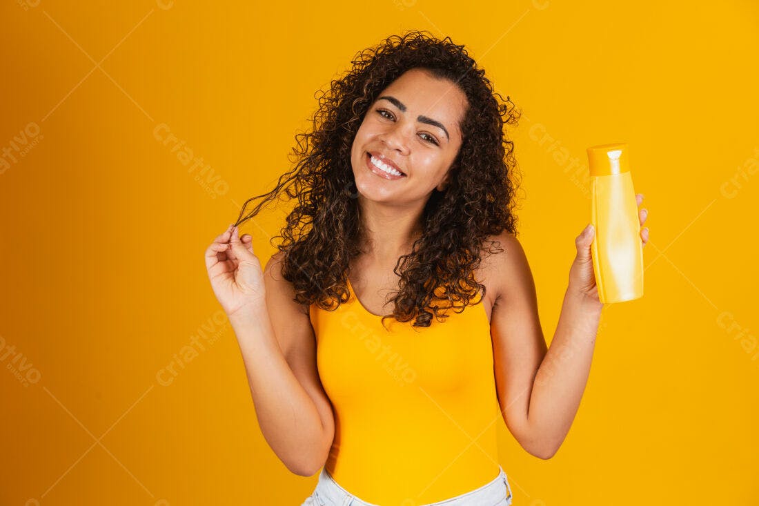 Mulher sorridente com cabelo cacheado segurando shampoo amarelo