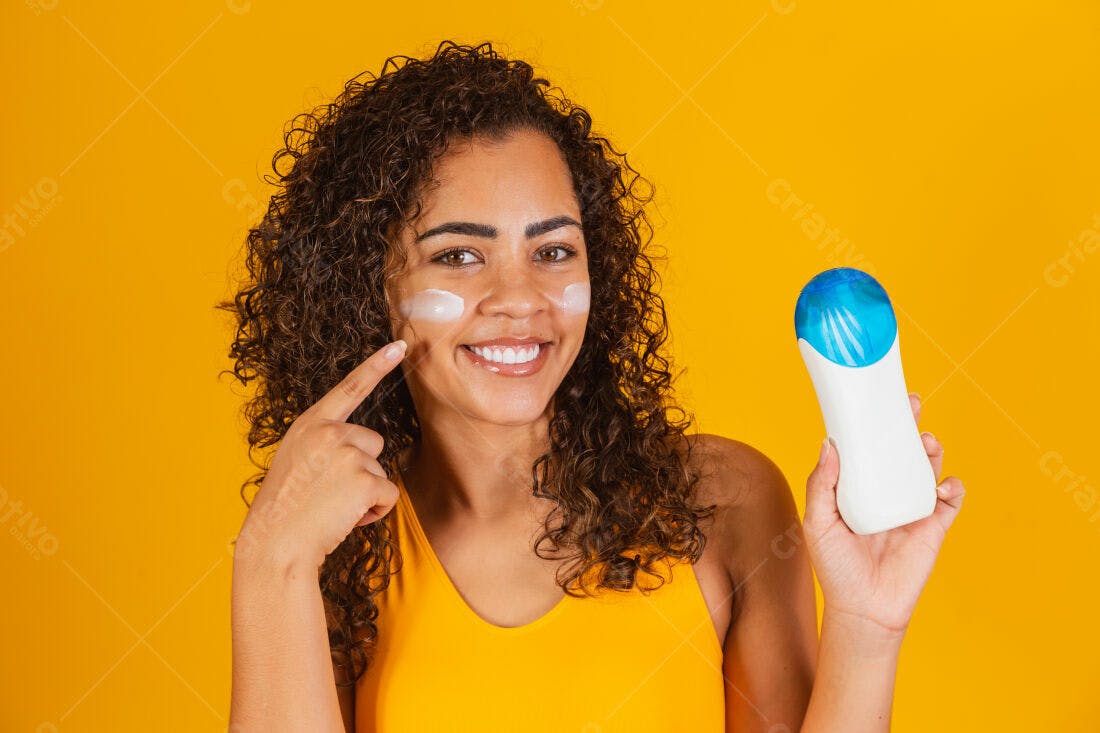 Mulher aplica protetor solar fundo amarelo