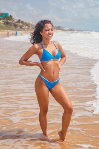 Mulher bonita morena na praia de biquíni azul fazendo pose 4