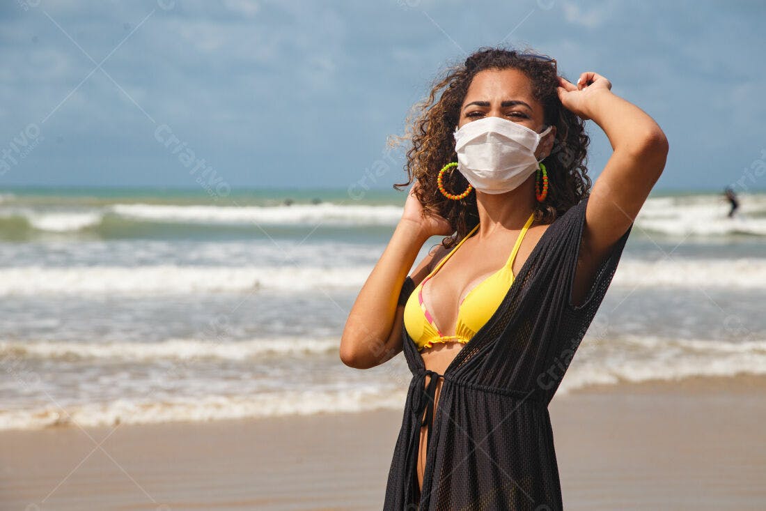 Mulher na praia com máscara facial