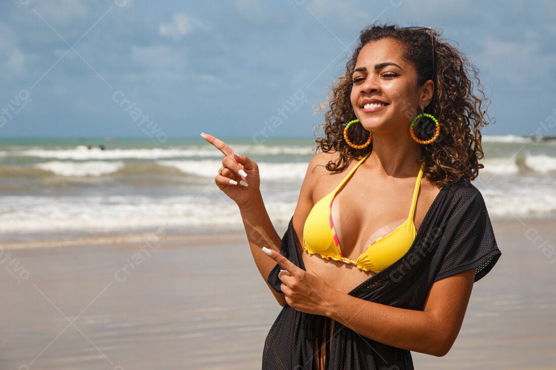 Mulher na praia apontando com biquini amarelo