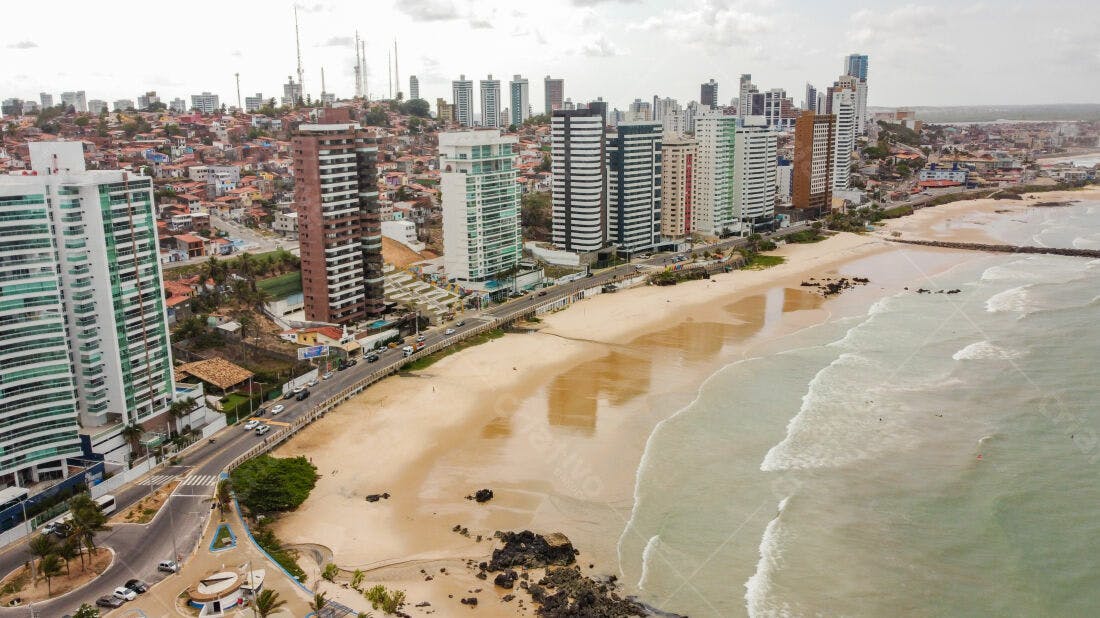 Praia urbana com prédios altos e ondas suaves