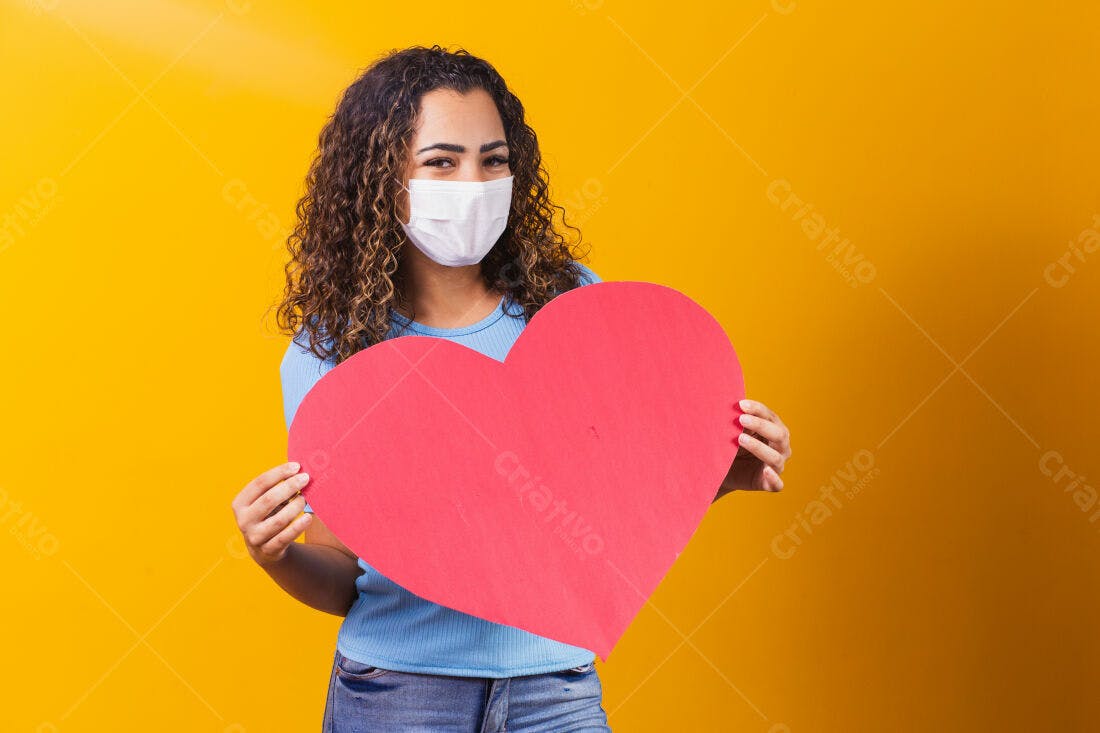 Mulher com máscara segurando coração vermelho