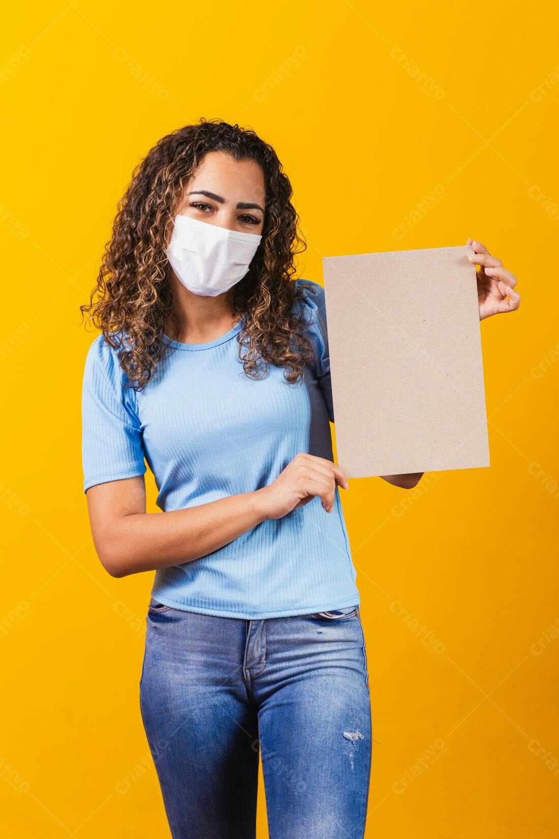 Mulher com máscara segurando cartaz fundo amarelo