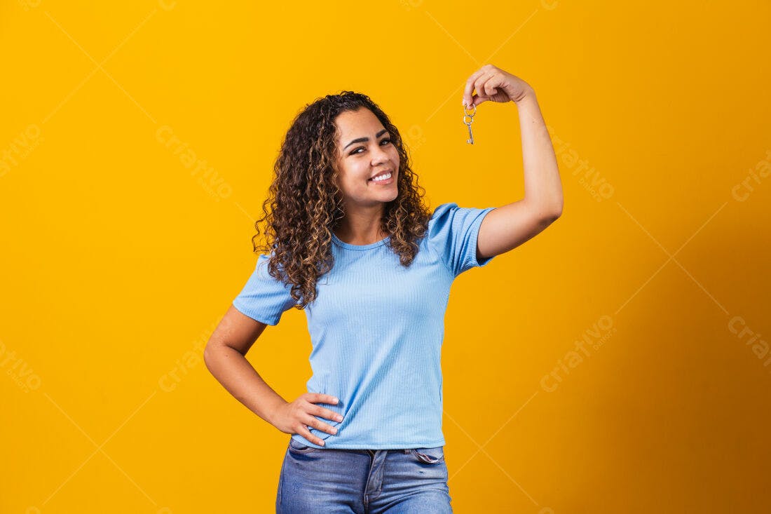 Mulher jovem mostrando chave fundo amarelo