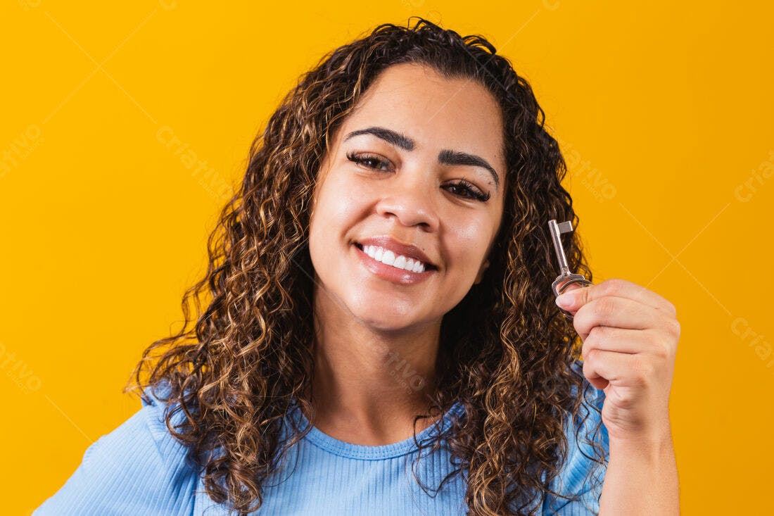 Mulher sorrindo segurando chave fundo amarelo