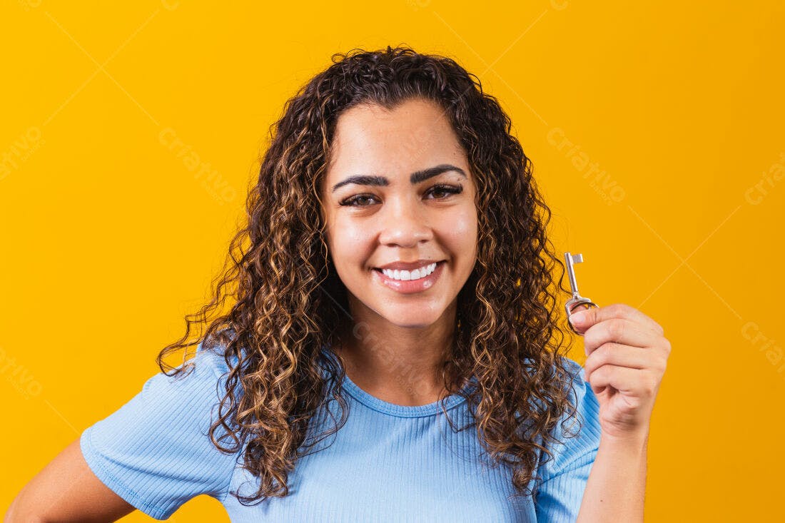 Mulher sorridente segurando chave fundo amarelo