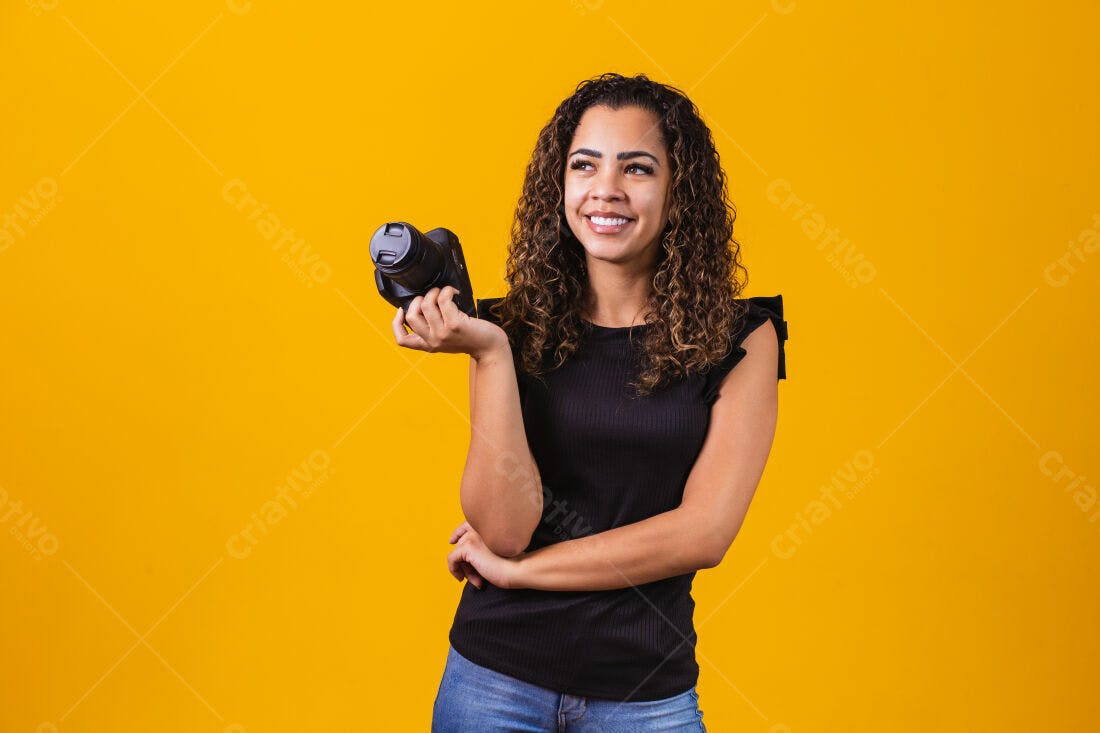 Fotógrafa sorridente segurando câmera fundo amarelo