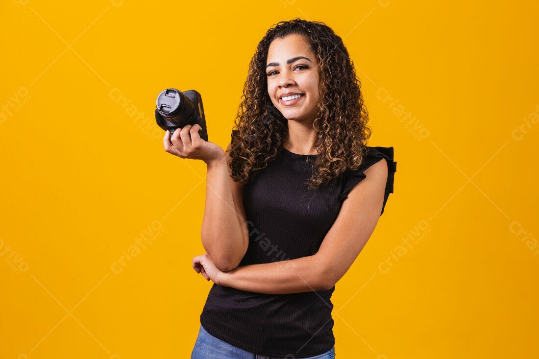 Fotógrafa sorridente segurando câmera fundo amarelo
