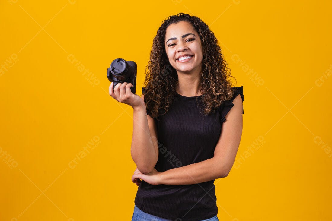Fotógrafa sorridente segurando câmera fundo amarelo