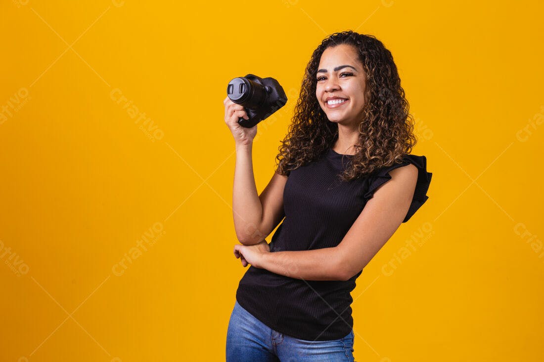 Fotógrafa sorridente segurando câmera fundo amarelo