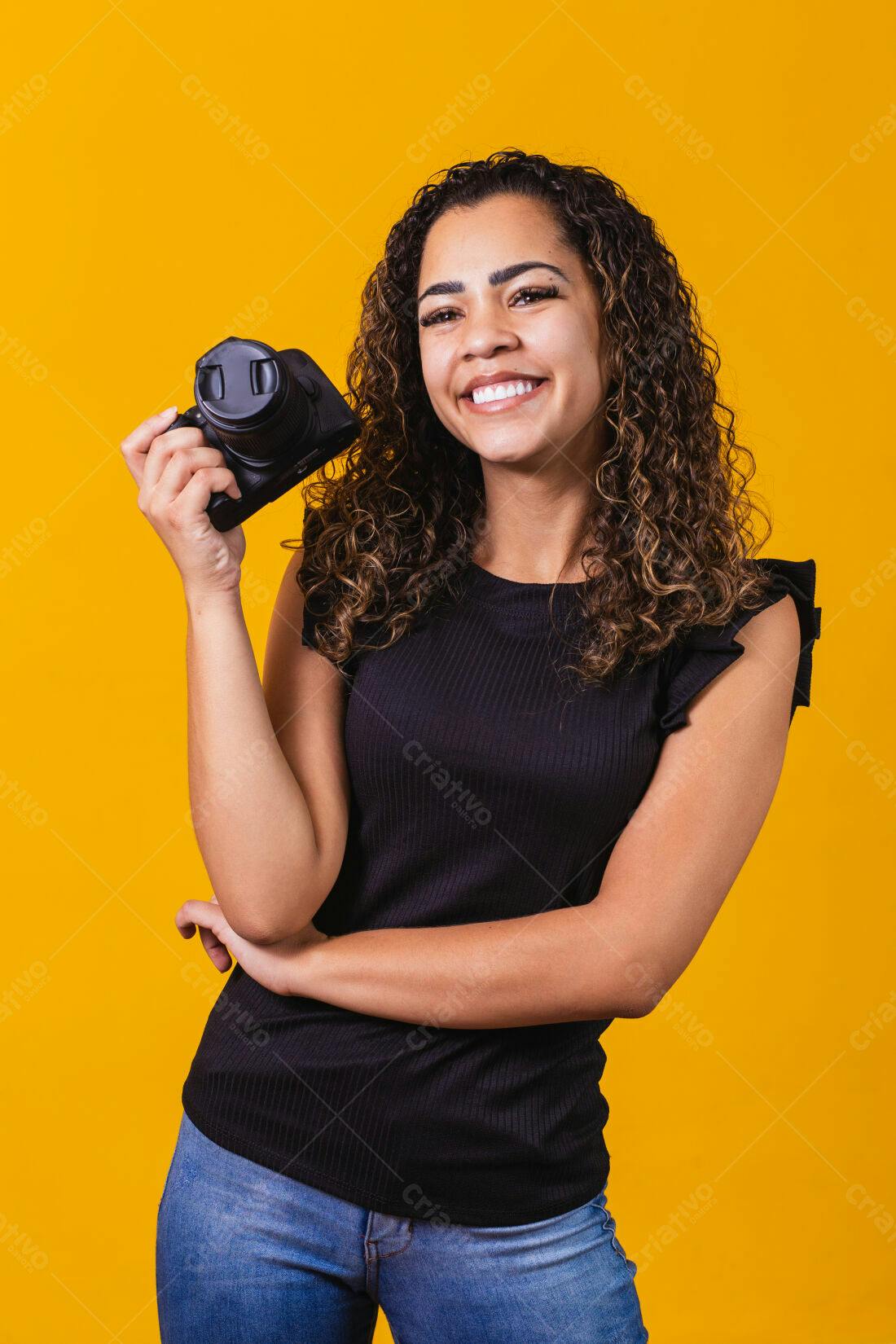 Fotógrafa sorridente segurando câmera fundo amarelo