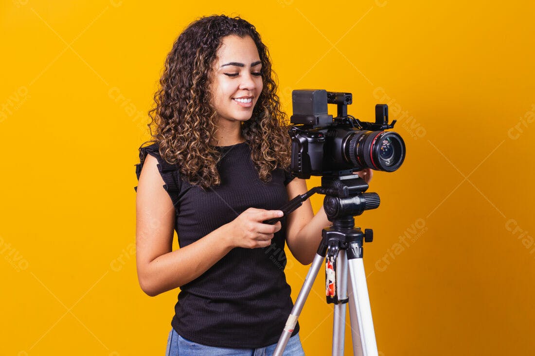 Mulher operando câmera profissional fundo amarelo
