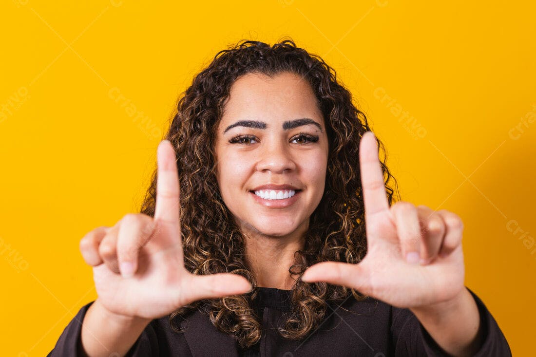 Mulher sorridente com mãos em formato de moldura fundo amarelo