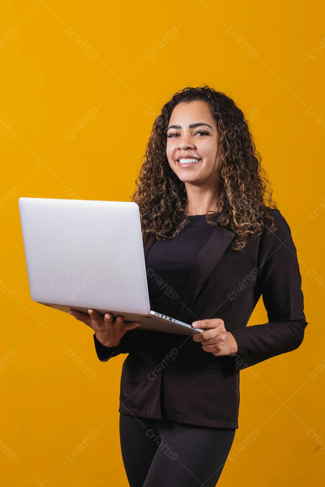 Mulher negra sorrindo com notebook fundo amarelo