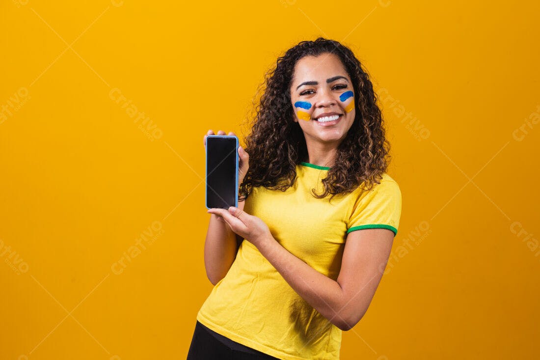 Mulher sorridente mostra celular fundo amarelo