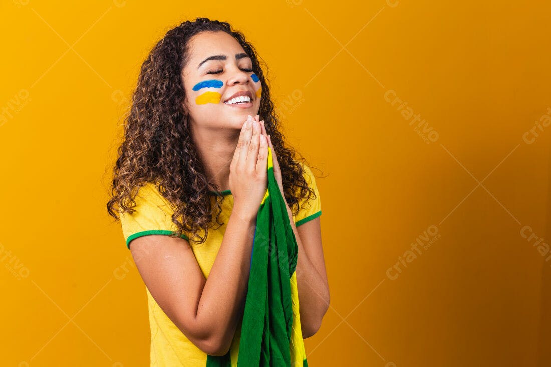 Torcedora brasileira em oração com bandeira