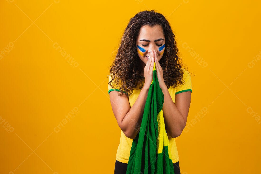 Torcedora brasileira em oração com bandeira