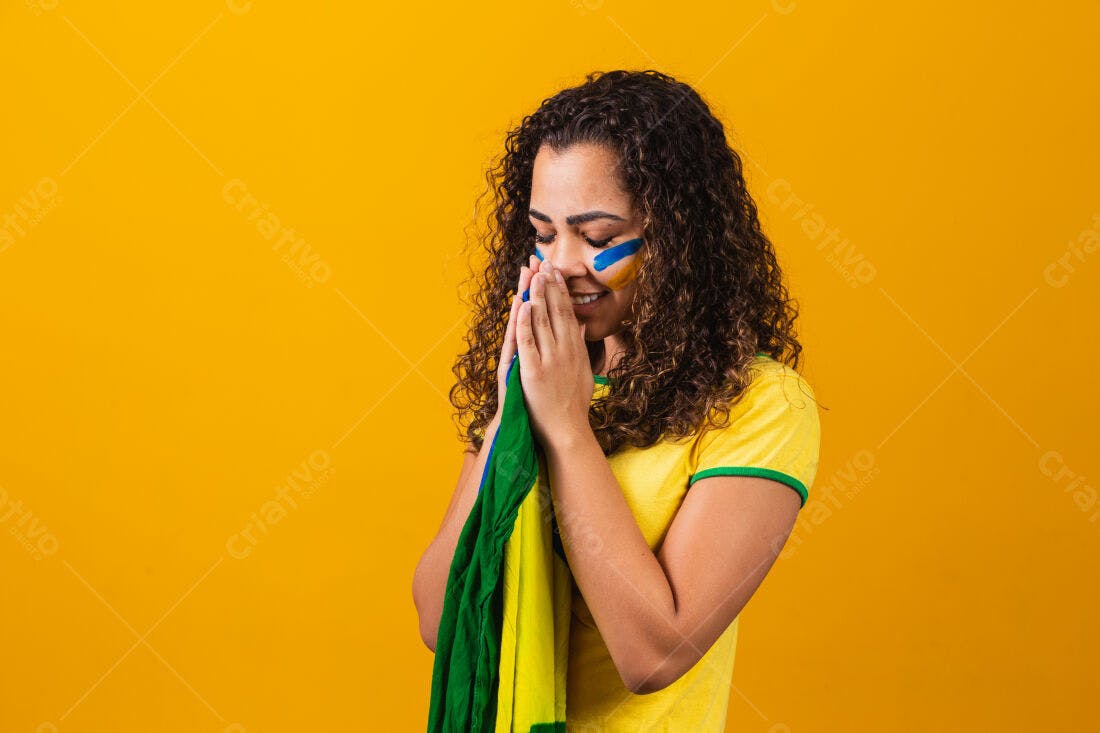 Torcedora brasileira em oração com bandeira