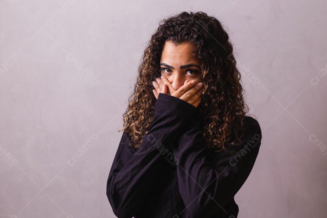 Mulher cobrindo a boca com as mãos fundo cinza