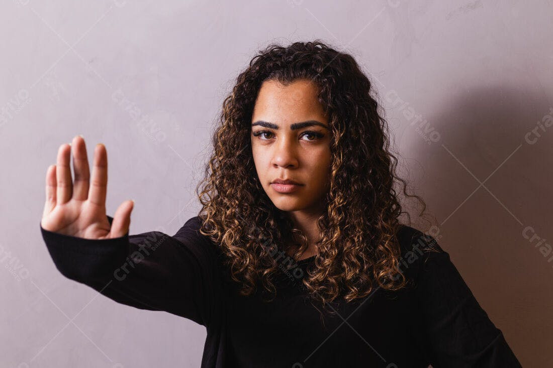 Mulher com cabelo cacheado mostrando gesto de parada
