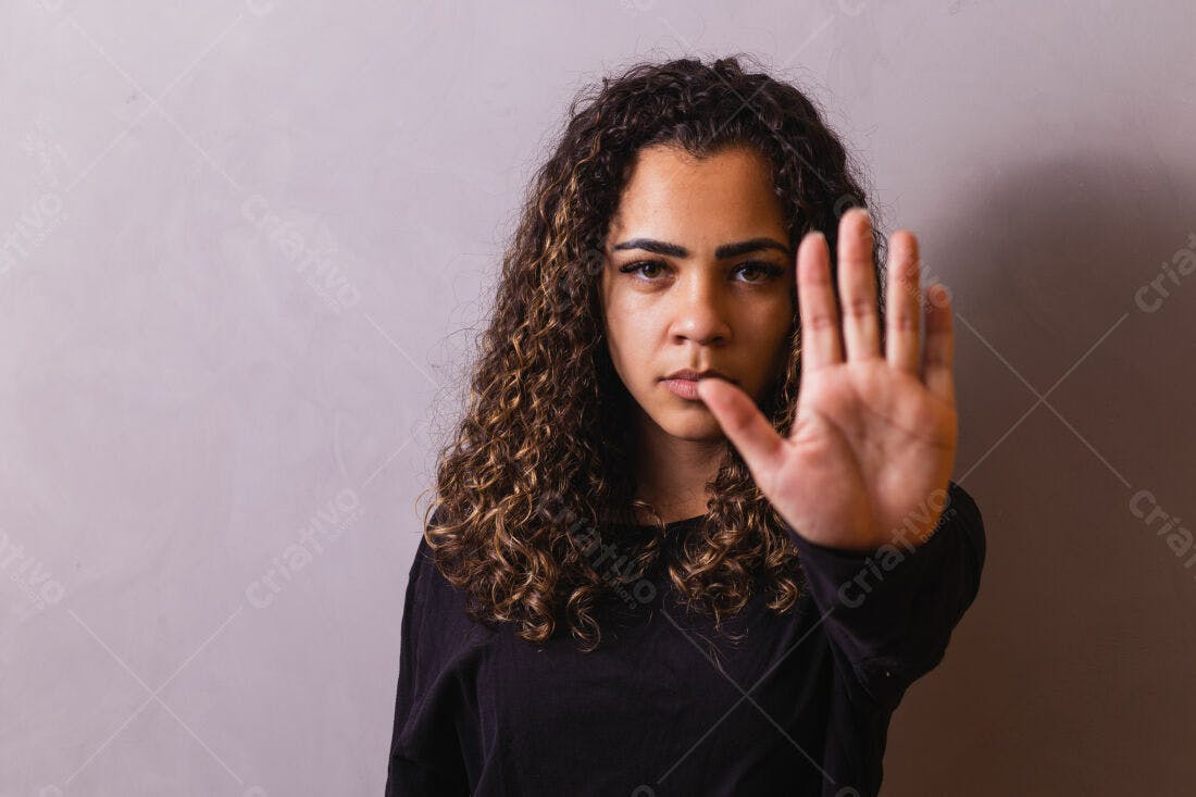 Mulher com cabelo cacheado mostrando a mão em sinal de parada