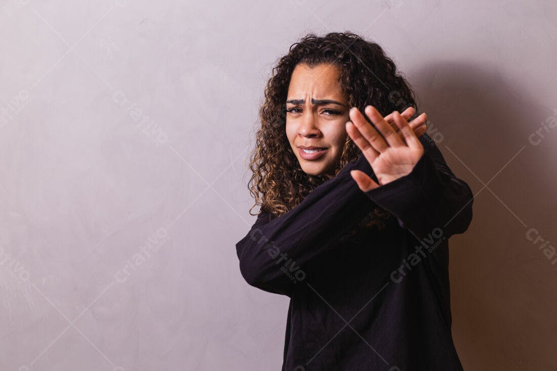 Mulher com cabelo cacheado fazendo sinal de pare