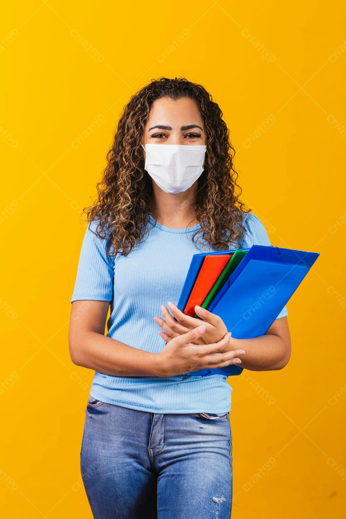 Estudante com máscara usando pastas coloridas