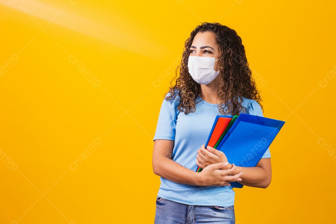 Estudante com máscara segurando pastas fundo amarelo