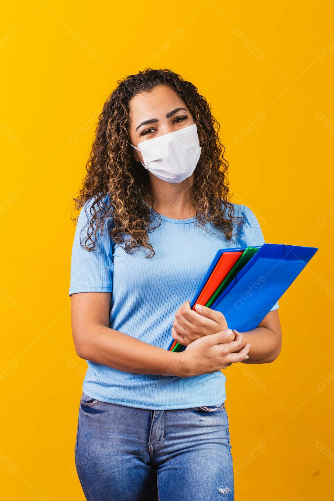 Mulher com máscara usando pastas coloridas fundo amarelo