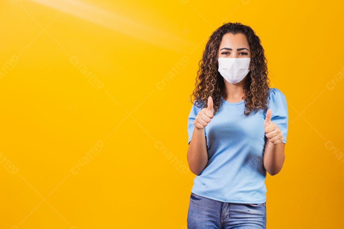 Mulher com máscara mostrando positivo fundo amarelo