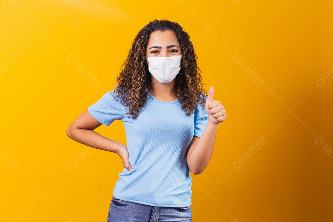 Mulher com máscara mostrando positivo fundo amarelo
