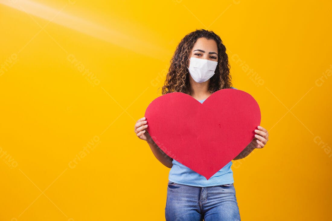 Mulher com máscara segurando coração vermelho