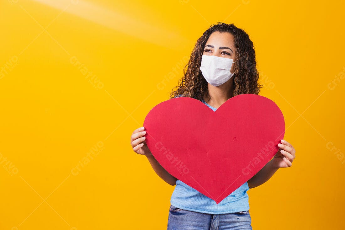 Mulher com máscara segurando coração vermelho