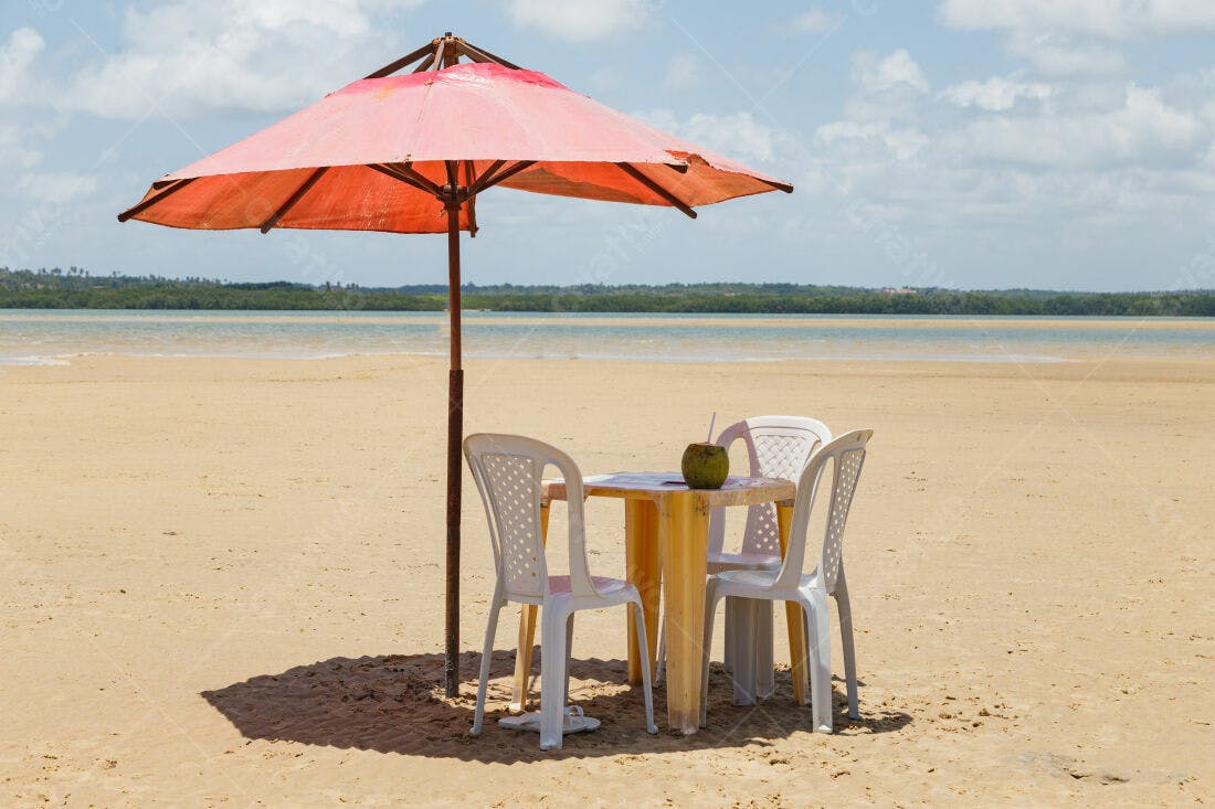 Mesa na praia com coqueiro e guarda-sol