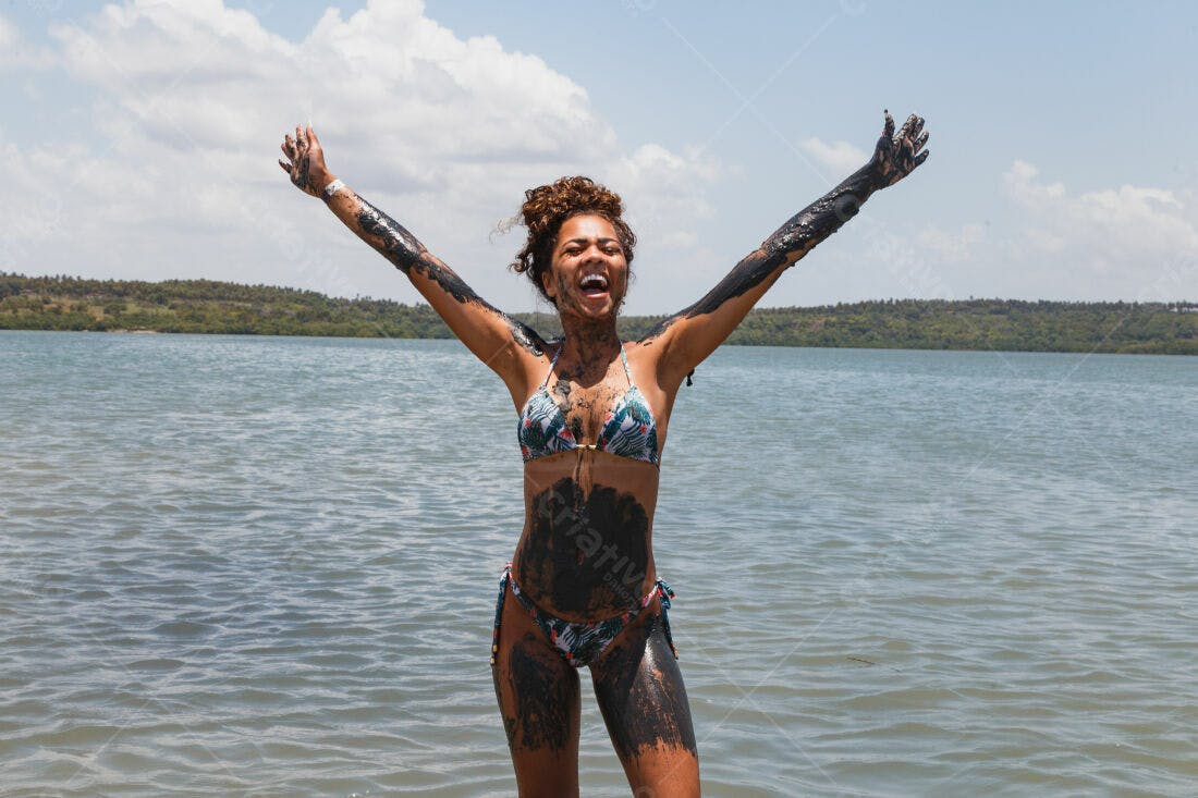 Mulher feliz coberta de lama em lagoa