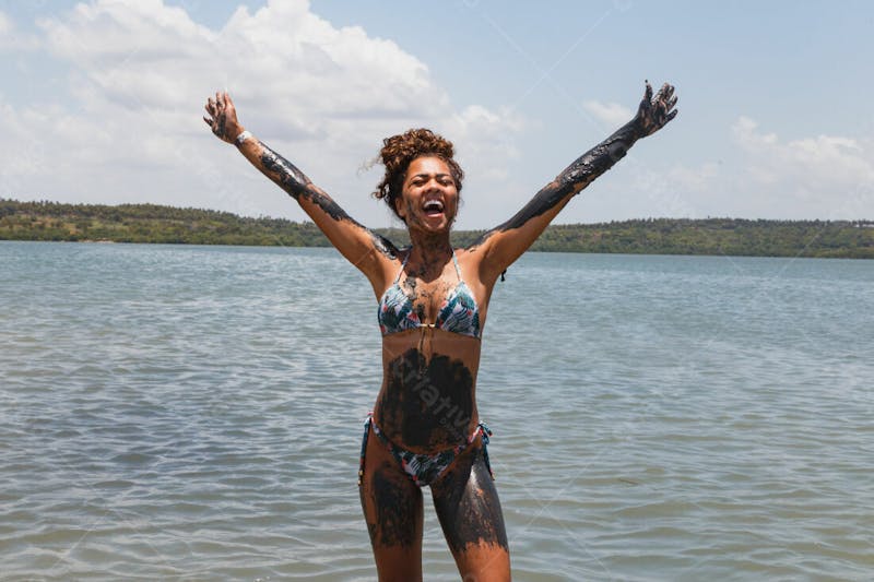 Mulher bonita morena feliz com braços abertos na praia corpo com barro