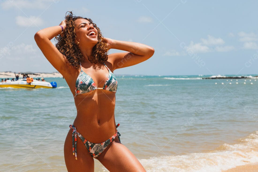 Mulher feliz na praia de biquini estampado