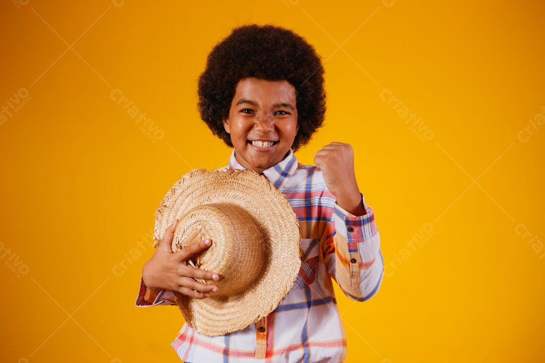 Menino afro sorridente com chapéu de palha fundo amarelo