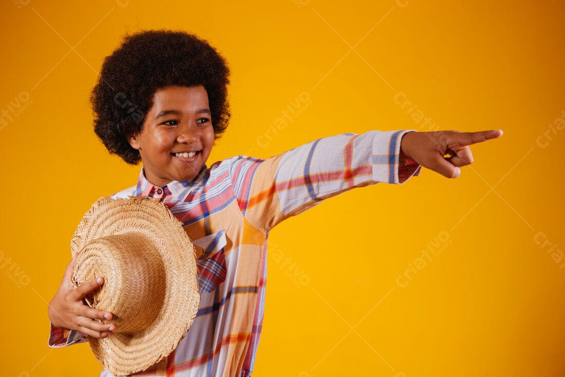 Menino sorridente apontando chapéu de palha fundo amarelo