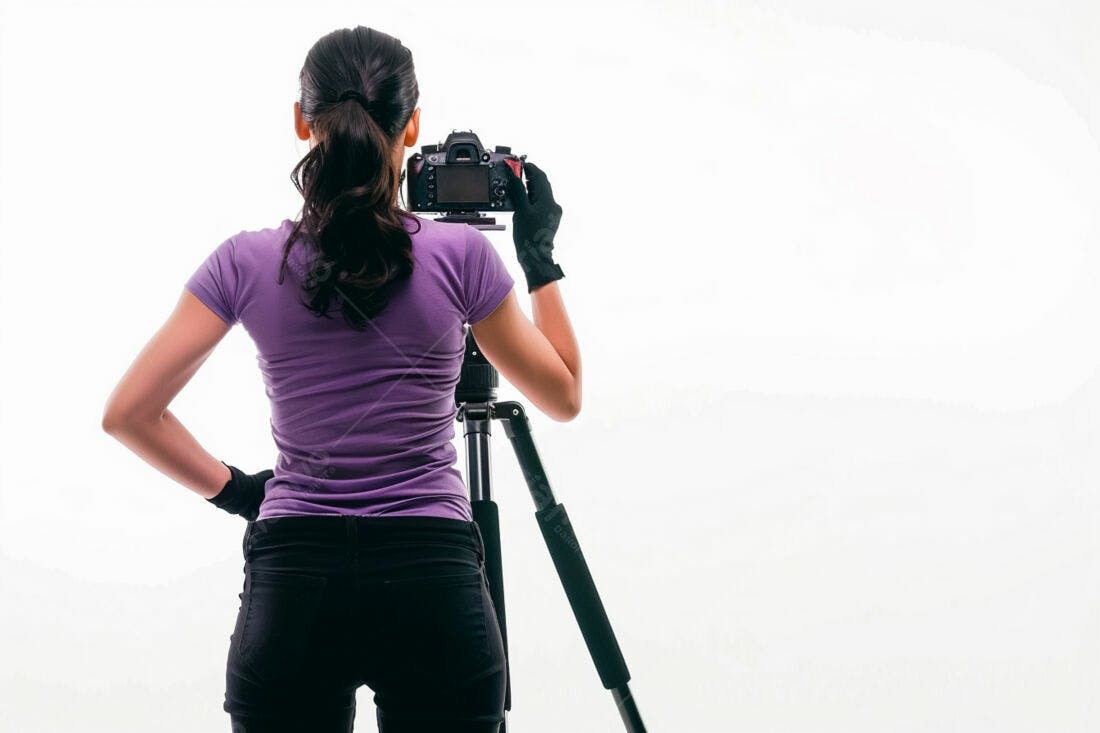 Fotógrafa com câmera em tripé fundo branco
