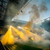 Modernized soccer stadium filled with smoke and illuminated by lights