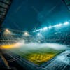 Modernized soccer stadium filled with smoke and illuminated by lights