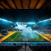 Modernized soccer stadium, full of smoke and illuminated by lights