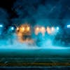 Modernized football stadium filled with smoke and illuminated by lights